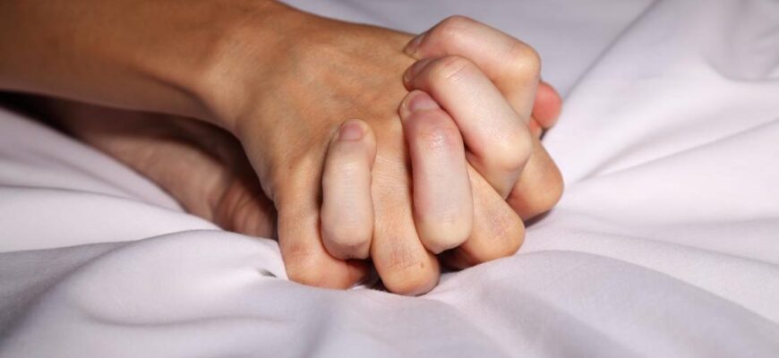 couple holding hands in bed during sex 1100x720 1