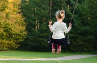 girl in white long sleeve shirt and black skirt sitting on swing during day time