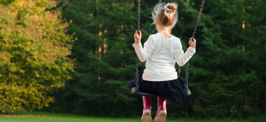 girl in white long sleeve shirt and black skirt sitting on swing during day time