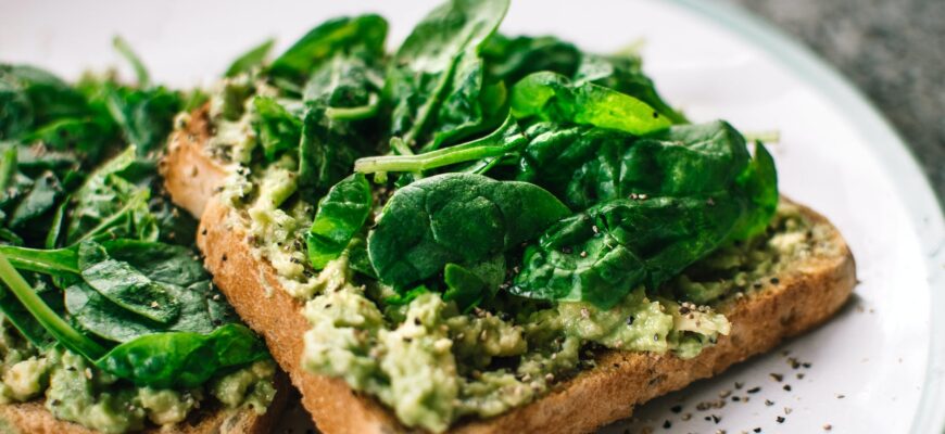 basil leaves and avocado on sliced bread on white ceramic plate