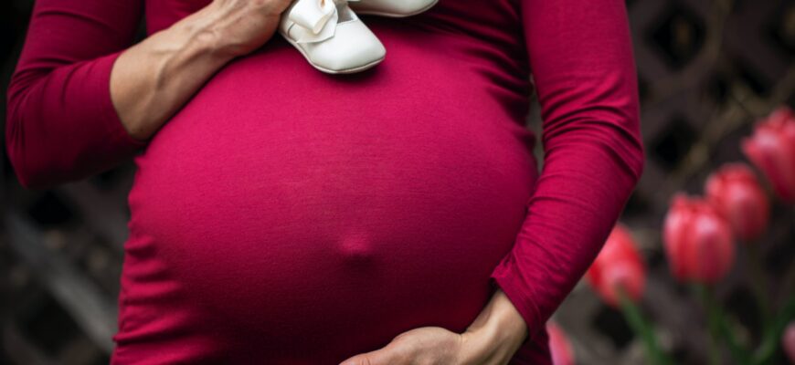 pregnant woman holding baby s shoes