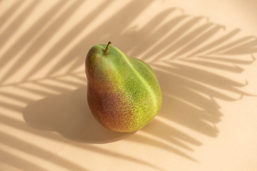 fresh organic fruit pear located against white surface in sunbeam