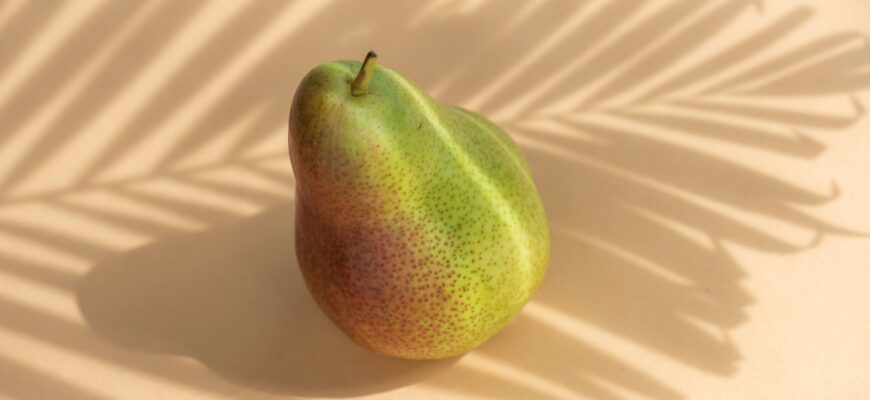 fresh organic fruit pear located against white surface in sunbeam