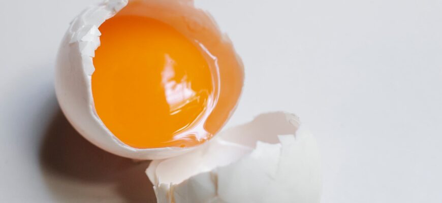 broken uncooked egg on white table