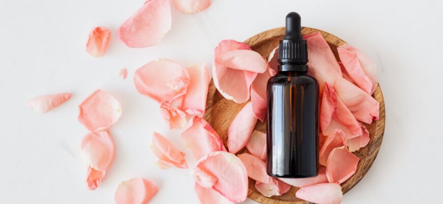 composition of cosmetic bottle with pink rose petals and wooden plate