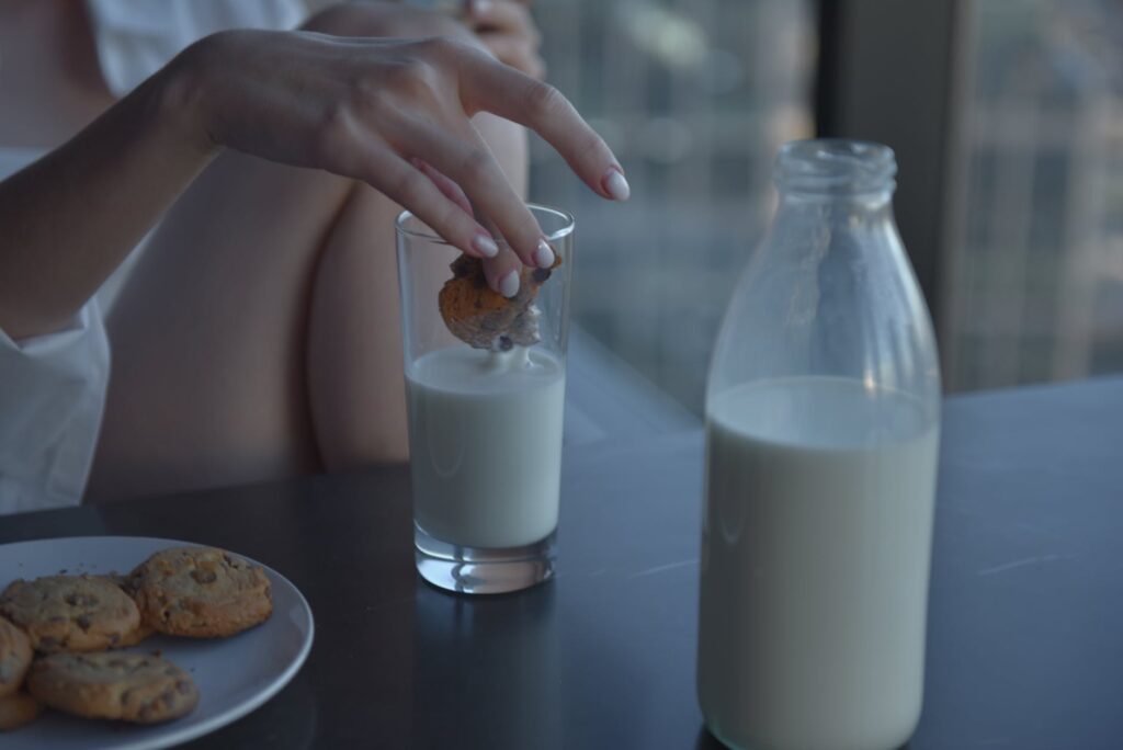 person holding clear glass bottle with milk