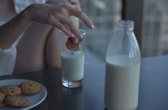person holding clear glass bottle with milk