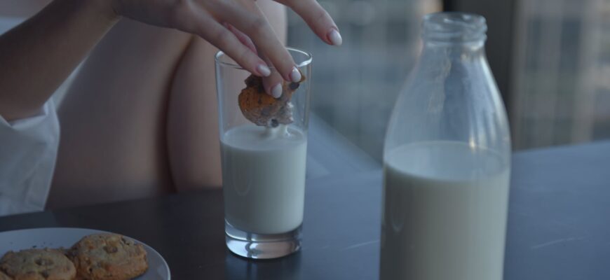 person holding clear glass bottle with milk