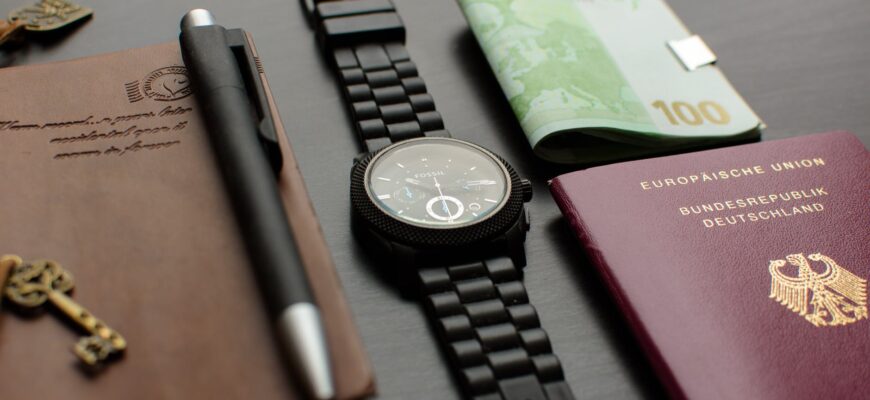 round black chronograph watch on table near germany passport an banknote on table