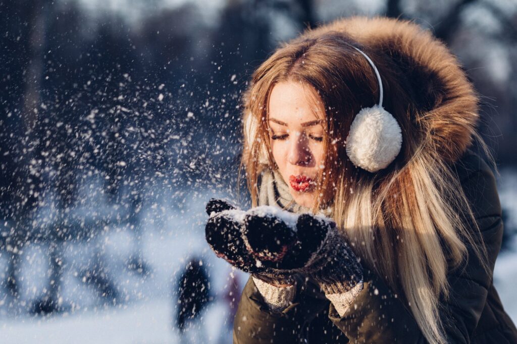 woman blowing snow from hand
