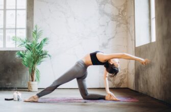 woman in gray leggings and black sports bra doing yoga on yoga mat