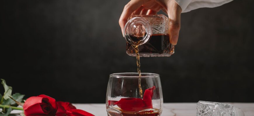 crop person pouring whiskey into glass