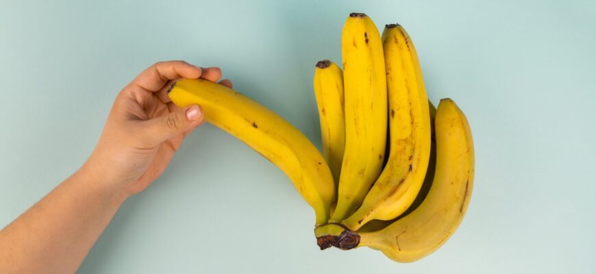 crop person with bunch of tasty fresh bananas