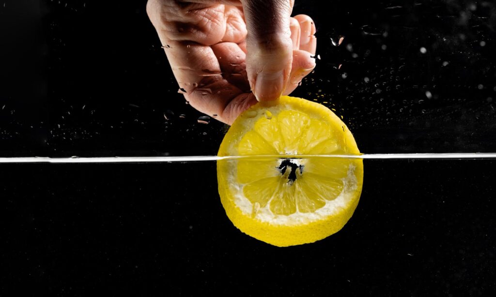 hand of a person dipping sliced lemon in water