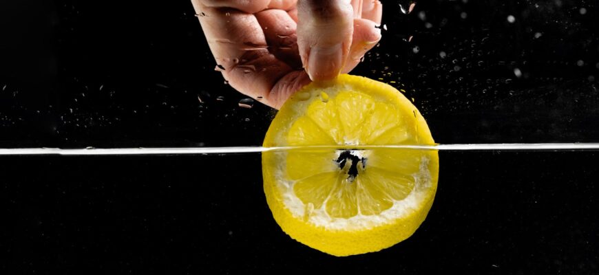 hand of a person dipping sliced lemon in water
