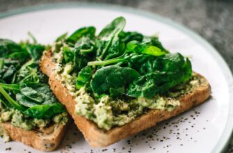 basil leaves and avocado on sliced bread on white ceramic plate