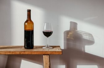 a bottle and a glass of wine on a wooden bench