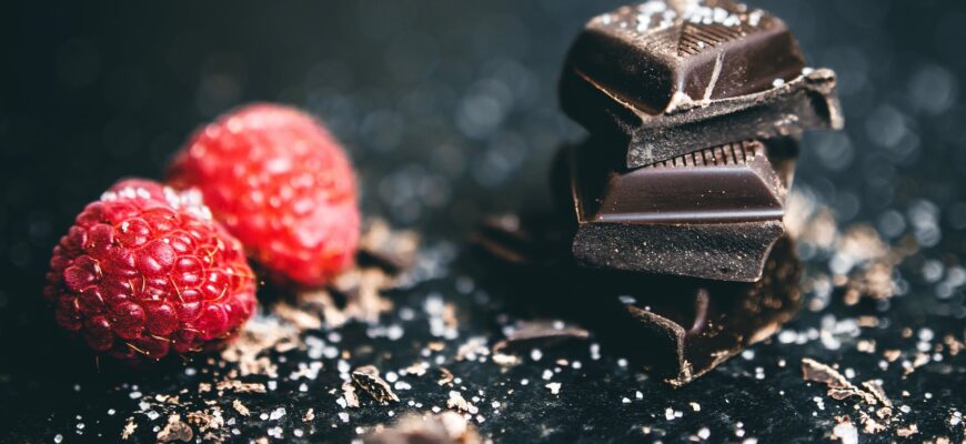 close up photo of stacked chocolates bars beside raspberries