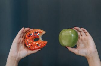 faceless woman showing fresh apple and sweet doughnut