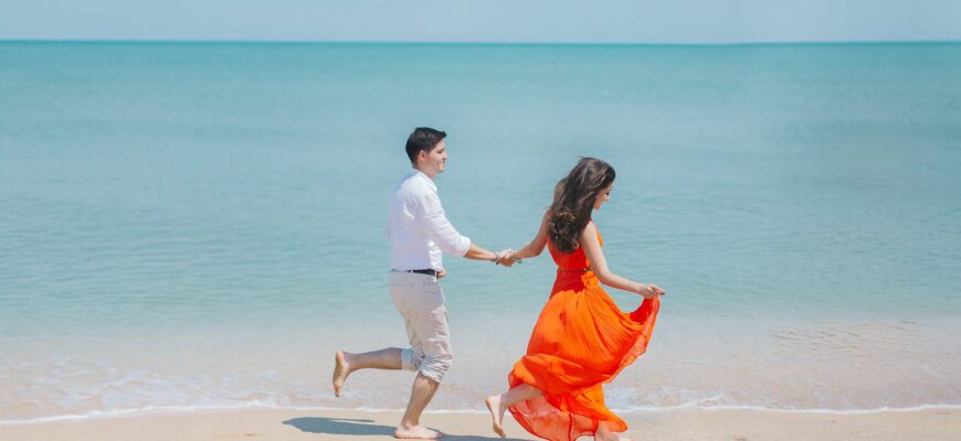 man and woman walks beside green sea