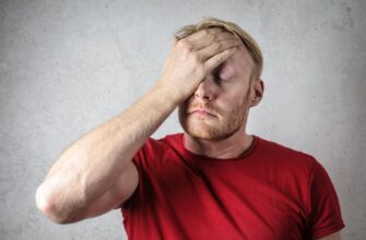 a man in red shirt covering his face