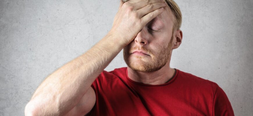 a man in red shirt covering his face