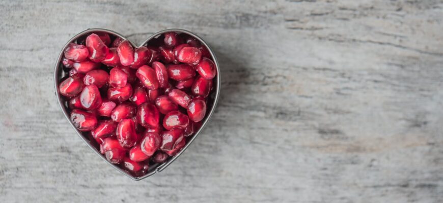 silver heart bowl filled of red pomegranate seeds