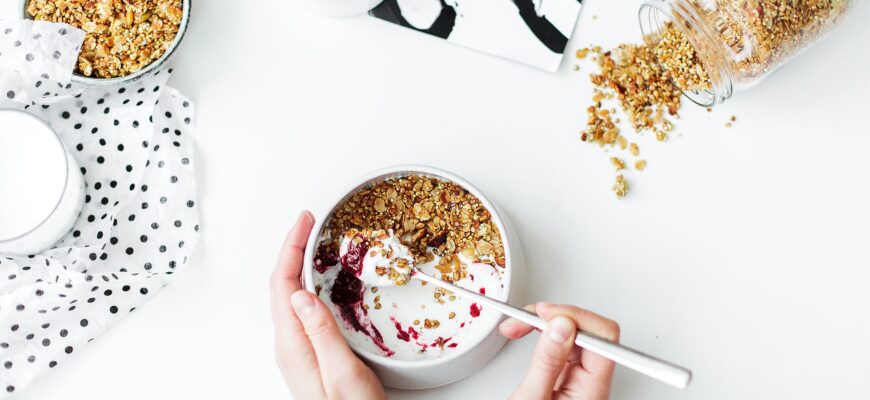 person mixing cereal milk and strawberry jam on white ceramic bowl
