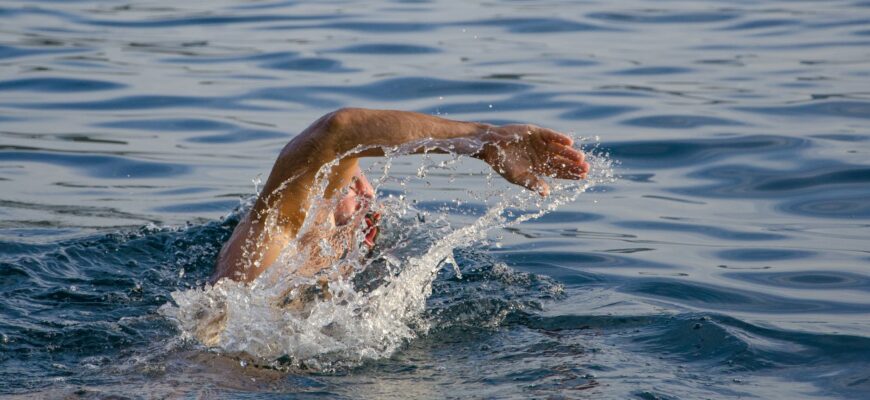 person swimming on body of water doing freestyle strokes