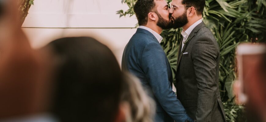 men wearing suit kissing in front of people