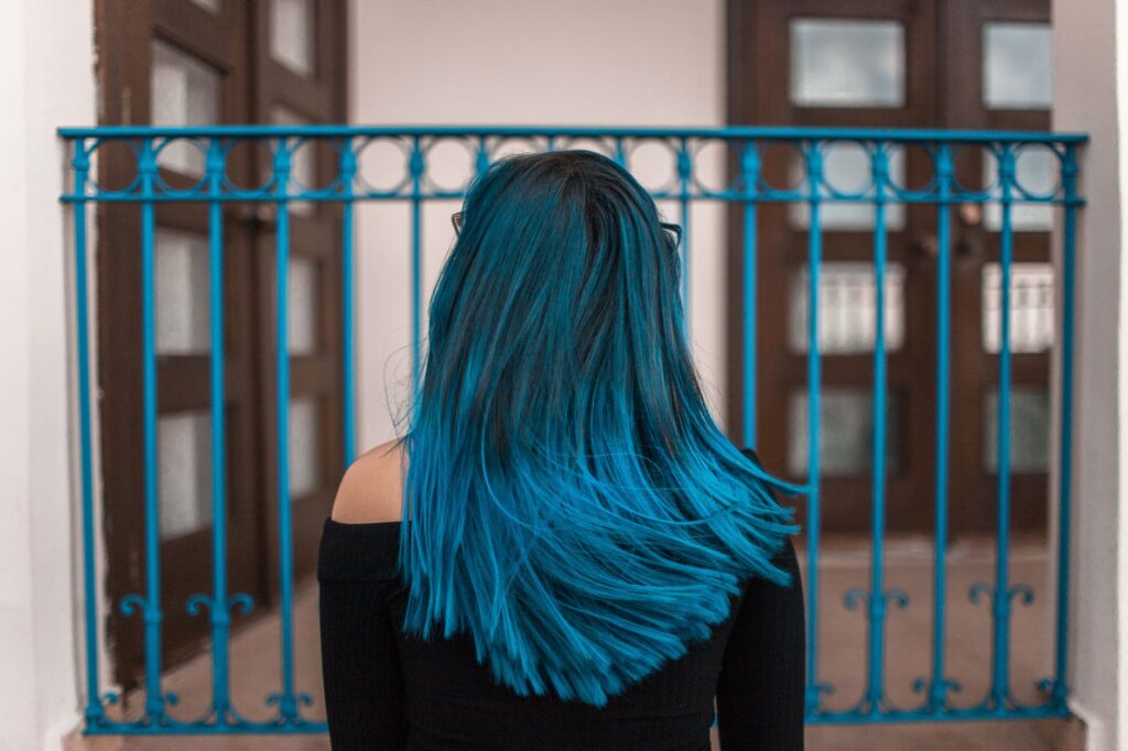 blue haired woman facing metal fence