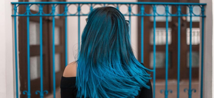 blue haired woman facing metal fence