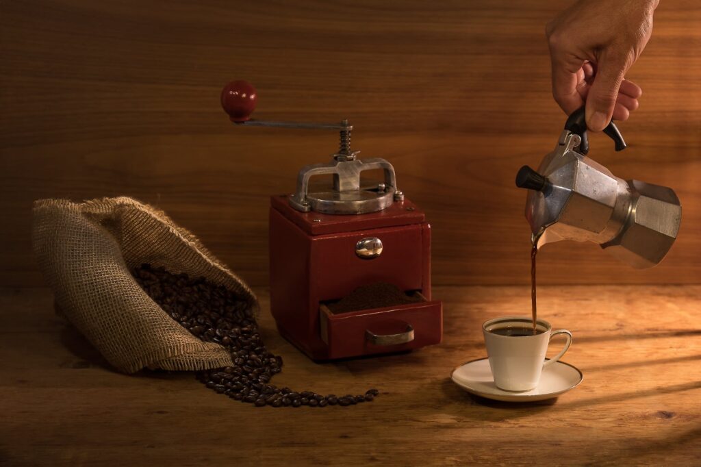 a close up shot of a person pouring coffee from a moka pot