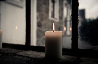 pillar candle near clear glass window