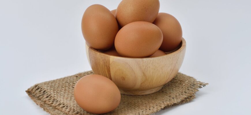 brown eggs on brown wooden bowl on beige knit textile