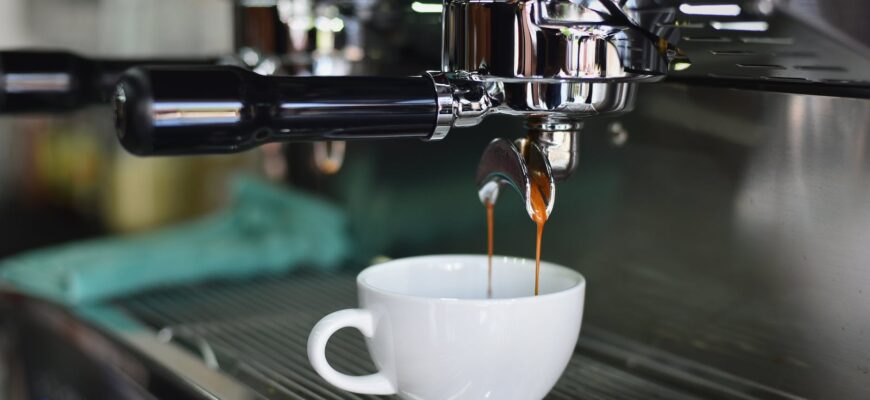 white ceramic mug on espresso machine filling with brown liquid