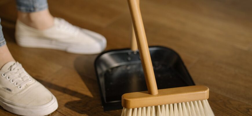 person wearing white pants and white socks standing beside brown broom