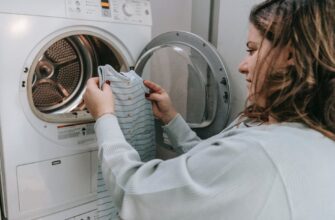 happy mother washing baby clothes in machine