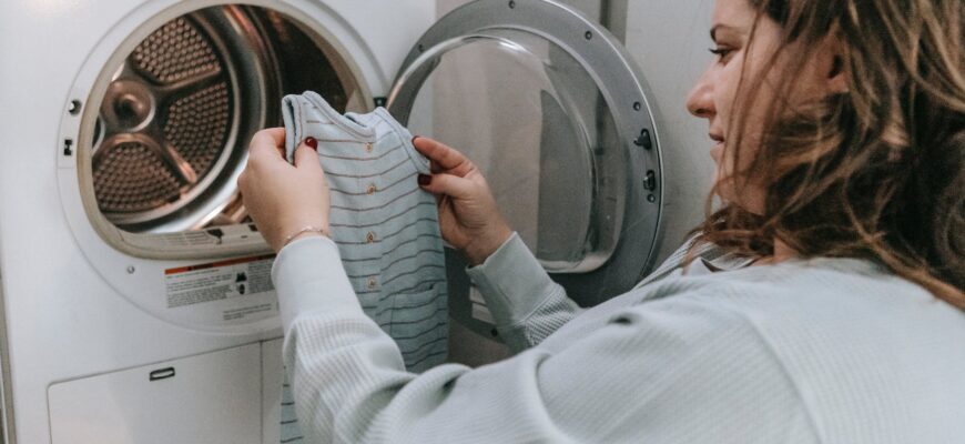 happy mother washing baby clothes in machine