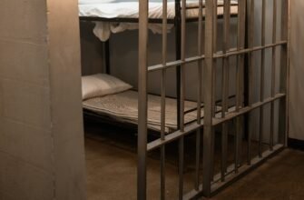 a bunk bed with striped linen behind bars