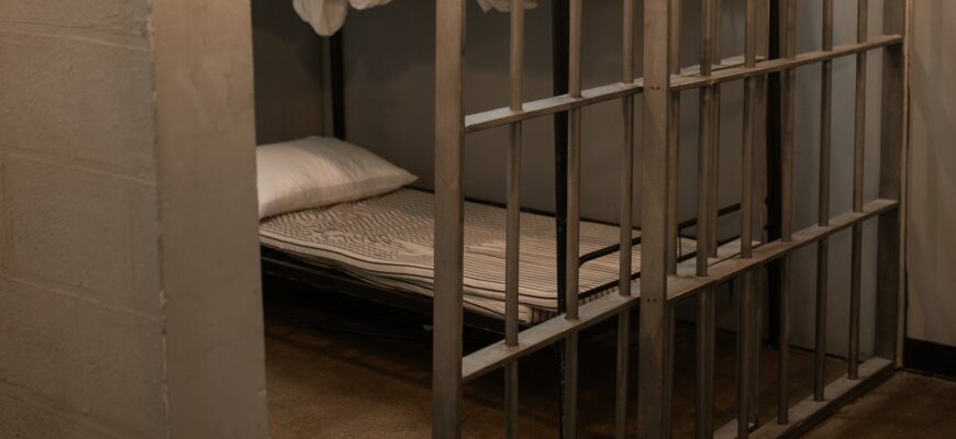 a bunk bed with striped linen behind bars