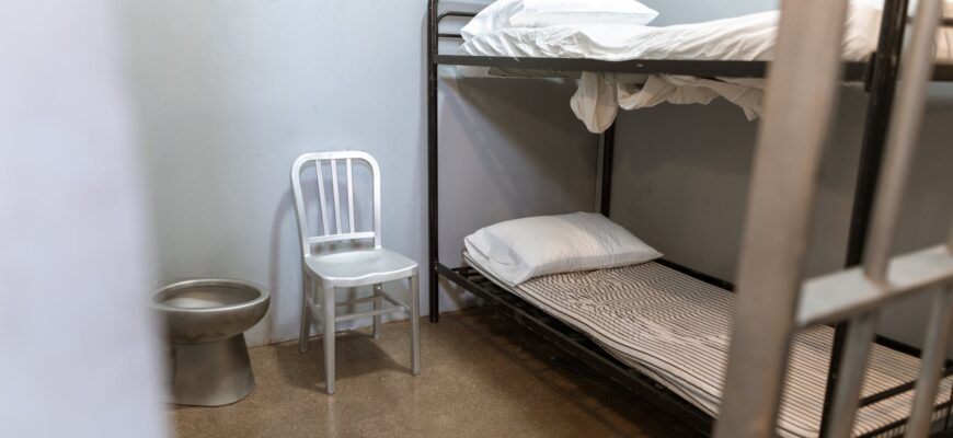 a bunk bed with striped foam mattress in a prison cell