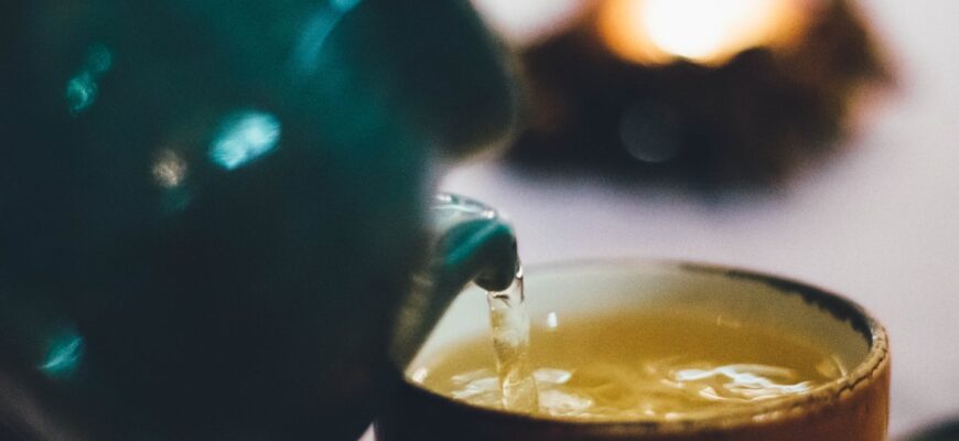 person pouring liquid into brown ceramic cup