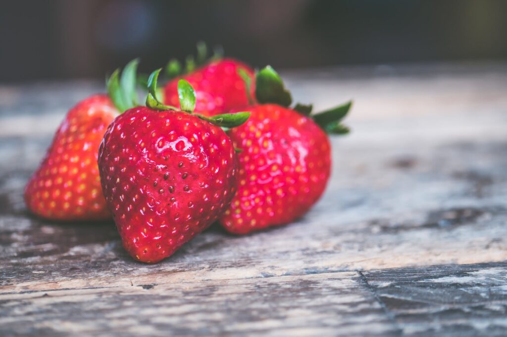 shallow focus photo of strawberries on gray wooden surface