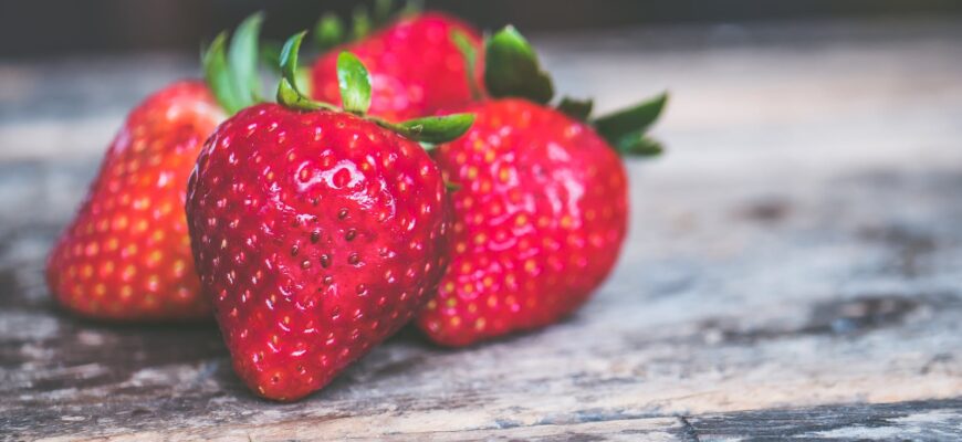 shallow focus photo of strawberries on gray wooden surface
