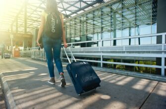 woman walking on pathway while strolling luggage