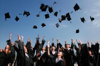 newly graduated people wearing black academy gowns throwing hats up in the air