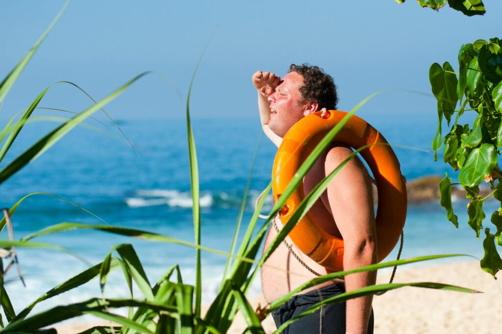 orange safety ring on man shoulder near body of water