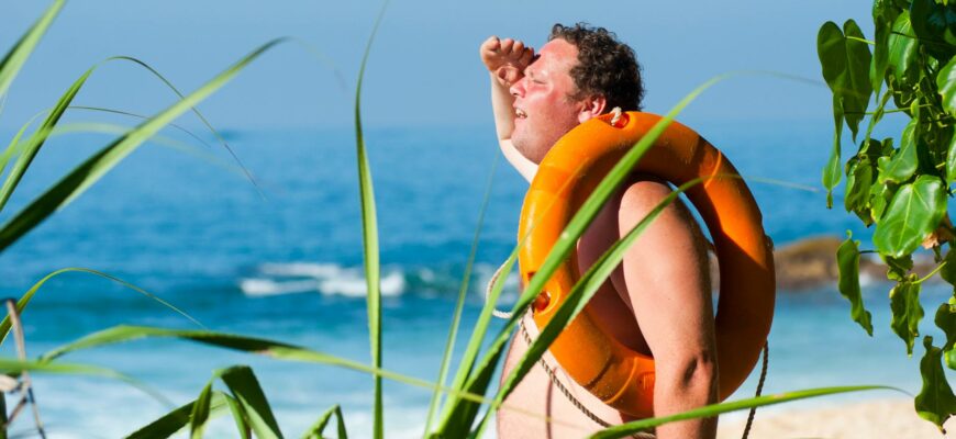 orange safety ring on man shoulder near body of water