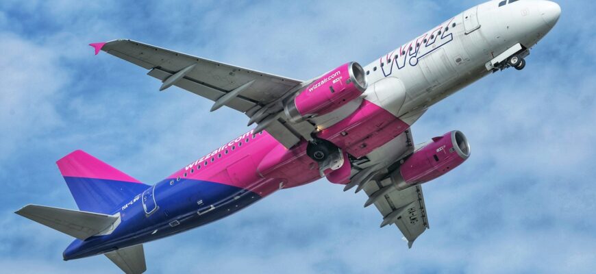 a pink and blue jet airliner flying in the sky